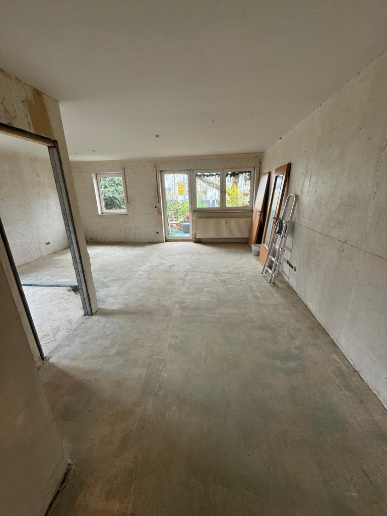 Großer leerer Wohnbereich mit vorbereiteten Wänden und Boden für Malerarbeiten